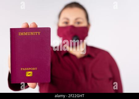 Femme avec masque de protection marron portant immunité coronavirus électronique Passport. Concept de déplacement libre et de fin de restriction. Gris Banque D'Images