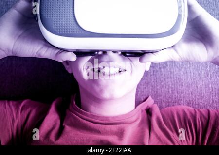 Jeune homme s'amusant avec la technologie des lunettes de réalité virtuelle sur le canapé à la maison. Un garçon souriant avec un casque vr. Technologie, style de vie moderne et Banque D'Images