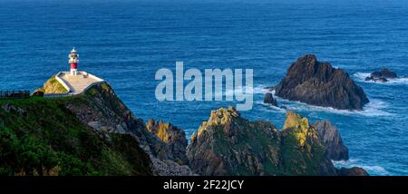 Un panorama du phare de Cabo Ortegal en Galice avec falaises vertes et lumière du soleil et bleu profond oc Banque D'Images