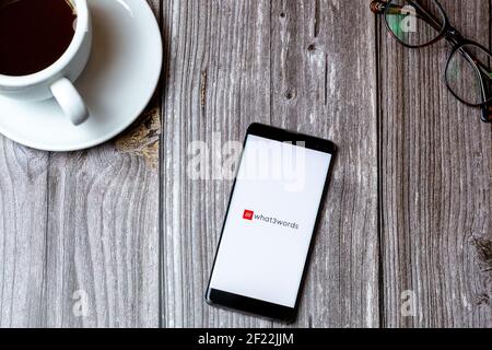 Un téléphone portable ou mobile posé sur un bois Tableau avec l'application What3words ouverte à l'écran à côté de un café Banque D'Images