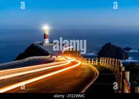 Des feux de remorque lumineux mènent au phare de Cabo Ortegal à nuit Banque D'Images