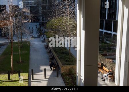 Alors que les employés de bureau restent à la maison conformément aux directives du gouvernement Covid et aux politiques individuelles de l'entreprise, certains Londoniens bénéficient d'un soleil de printemps chaud sous Bassishaw Highwalk dans la City de Londres, le quartier financier de la capitale, lors du troisième confinement de la pandémie du coronavirus, le 9 mars 2021, à Londres, en Angleterre. Banque D'Images