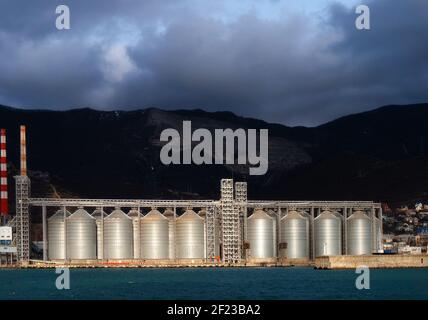 citernes pour le stockage du grain dans le port au bord de la mer en toile de fond de la montagne Banque D'Images