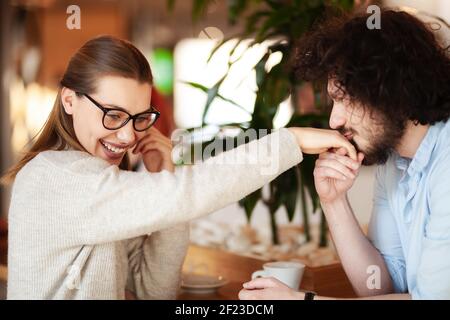 Couple charmant ayant une réunion dans un café-bar. Garçon embrassant la main de la fille. Banque D'Images