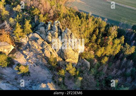 06 mars 2021, Saxe-Anhalt, Timmenrode: Les premiers rayons du soleil de la journée frappent le Hamburger Wappen. (Photo prise avec un drone) la formation de grès fait partie d'un sentier de crête populaire qui serpente du Großvaterfelsen près de Blankenburg au Hamburger Wappen près de Timmenrode. En passant par des roches bizarsees avec des noms imaginatifs tels que Schweinekopf (tête de porc), Zwergenhöhe (hauteur de nain) ou Teufelskessel (chaudron du diable), il y a toujours des vues impressionnantes sur les mondes de montagne du Harz le long du chemin. La partie du sentier de crête dans la région du mur du Diable, également kno Banque D'Images