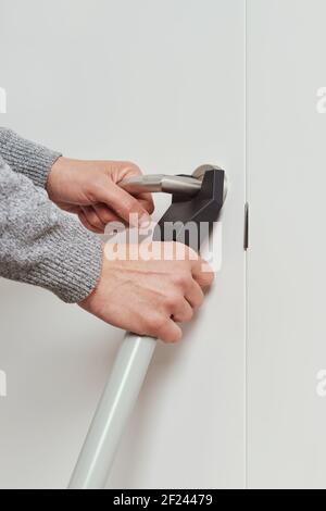 gros plan d'un jeune homme caucasien qui installe un cache-porte barre de sécurité dans la porte blanche de sa maison Banque D'Images