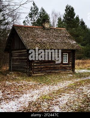 Sauna en bois maison en bois dans les bois en hiver. Bois brun distinctement. Des feuilles d'automne orange et un peu de neige sur la route sont visibles sur la route. Banque D'Images