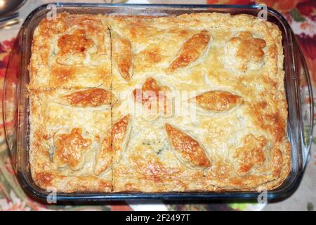 tarte à la viande maison à la croûte dorée, décorée d'ornement de pâte, rafraîchit dans un plat de cuisson en verre dans lequel elle a été préparée. coupes pour la division de la tarte Banque D'Images