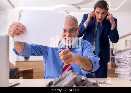 Un jeune homme et un vieux patron brûlent des papiers sur le lieu de travail Banque D'Images