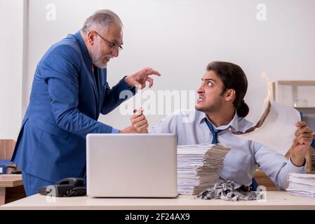 Un jeune homme et un vieux patron brûlent des papiers sur le lieu de travail Banque D'Images