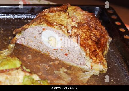 Pain de viande fait maison avec des œufs en feuilles de chou de Savoie. Dernière moitié, sur plaque de cuisson, dans son propre jus. Sur la coupe: Moitié de l'œuf entier, entouré de pain cuit Banque D'Images