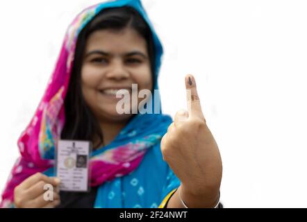 Accent sélectif sur le doigt marqué à l'encre d'une femme d'un village indien avec visage souriant et carte de vote de l'autre main Banque D'Images