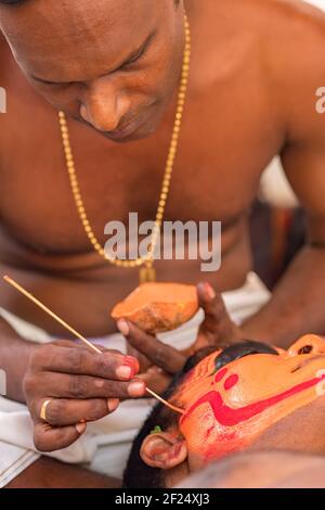 Payyanur, Inde - 5 décembre 2019 : le prêtre hindou fait le maquillage pour l'interprète de Theyyam pendant le festival du temple à Payyanur, Kerala, Inde. Theyyam est un po Banque D'Images