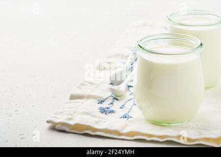 Crème aigre ou yaourt naturel dans un pot en verre avec des cuillères, concept santé et régime sur fond d'ardoise gris clair. Banque D'Images