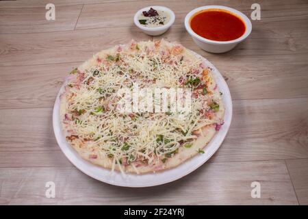 Uthappam ou Uttapam est un type de dosa du sud de l'Inde qui est plus épais, avec la tomate, l'oignon, les paquets de piment et le fromage Banque D'Images