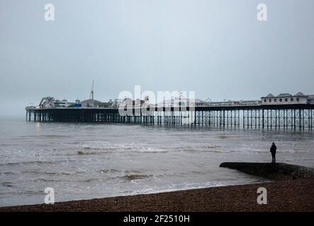 Le Palace Pier Brighton lors D'UNE soirée de Cold Winters avec Une seule personne debout avec son dos à la caméra Sur UN Groyne dans le Foreground Banque D'Images