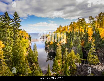 Magnifiques reflets de nuages et de couleurs automnales sur la rivière Baptême où elle rencontre le lac supérieur au parc national de Tettegouche, Minnesota Banque D'Images