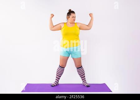 Les femmes caucasiennes curvy dans des vêtements lumineux isolés sur fond de studio. Le concept des jeunes et de l'obésité. Banque D'Images