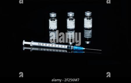 PRAGUE, CZE - 10 mars 2021. Ampoules de vaccin contre le virus du SRAS COVID-19. Vaccin mRNA de COMIRNATY sur fond noir. Seringue avec vaccin COMIRNATY contre S. Banque D'Images