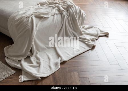 Partie intérieure de la chambre avec une couverture douce sur un lit et au sol Banque D'Images