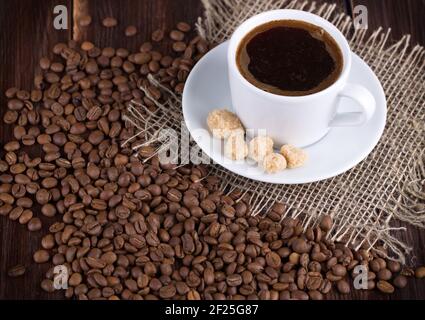 Tasse de café sur une soucoupe et grains de café sur un tableau Banque D'Images