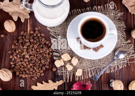 Tasse de café, crème, grains de café et sucre de canne sur une table Banque D'Images