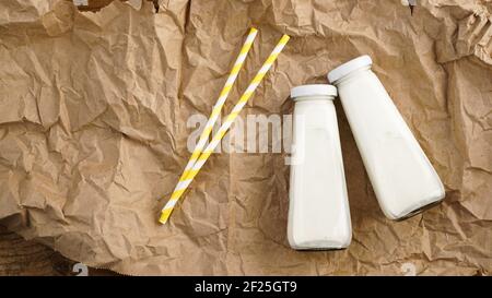 Lait de vache biologique en bouteilles de verre. Deux bouteilles de lait sur papier artisanal froissé Banque D'Images