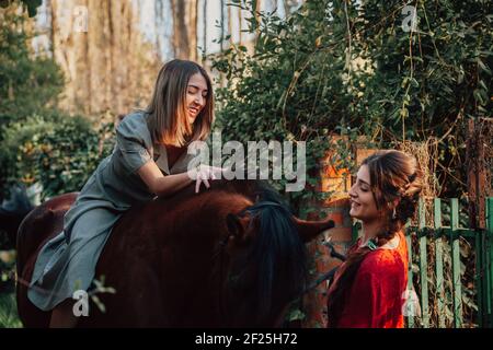 Deux femmes amis bavardent et prennent une promenade avec leur cheval à travers la campagne Banque D'Images