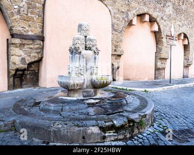 La Fontana delle Tiare est située sur le pavé de largo del Colonnato, à droite de l'arcade ouverte en 1933 le long des murs du Passetto. La fontaine a été construite en travertin par Pietro Lombardi en 1927. Sur une base tripartite robuste, il y a trois plateaux en forme de coquille semi-circulaire qui collectent l'eau versée par trois paires de becs, placés sur la tête des clés de Saint-Pierre et surmontés par trois tiaras papal sur lesquels un autre de couronnement: Les armoiries de Rome et celle du quartier Borgo sont sculptées dans les espaces entre les clés - Rome, Italie Banque D'Images