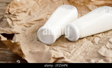 Lait de vache biologique en bouteilles de verre. Deux bouteilles de lait sur papier artisanal froissé Banque D'Images