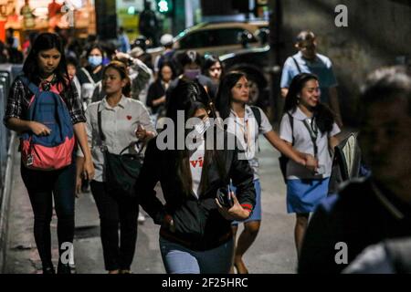 Les personnes portant un masque de protection traversent une rue tandis que le métro se prépare à une quarantaine communautaire renforcée pour lutter contre la propagation de la COVID-19 à Manille, aux Philippines. Banque D'Images