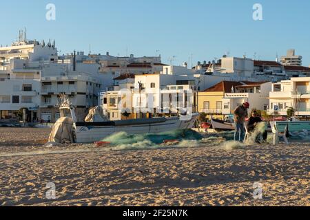 Pêcheurs sur la Praia dos Pescadores en train de réparer leur engrenage et filets Banque D'Images