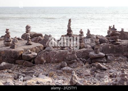 Des piles de pierres d'équilibrage ou de pierres équilibrées pour faire de la pierre ou de la pierre de cairns. Empilé ou empilé sur le rivage de la plage avec la mer derrière. Banque D'Images