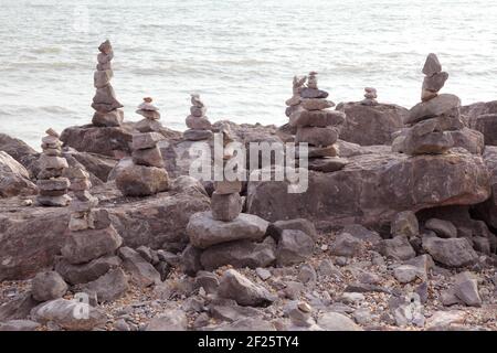 Des piles de pierres d'équilibrage ou de pierres équilibrées pour faire de la pierre ou de la pierre de cairns. Empilé ou empilé sur le rivage de la plage avec la mer derrière. Banque D'Images