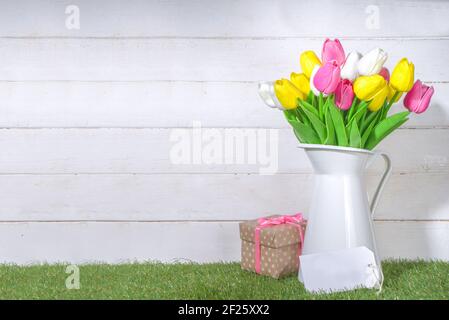 Carte de vœux de la fête des mères. Bouquet de tulipes en vase et étiquette de bienvenue sur bois blanc et planche en bois arrière-plan de l'espace de copie Banque D'Images