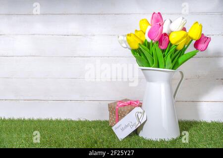 Carte de vœux de la fête des mères. Bouquet de tulipes en vase et étiquette de bienvenue sur bois blanc et planche en bois arrière-plan de l'espace de copie Banque D'Images