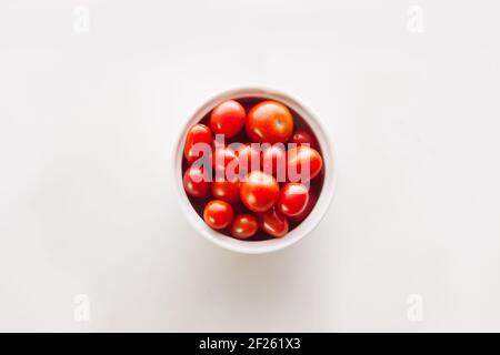 Bol en céramique rectangulaire et rond avec tomates cerises orange, jaune et rouge sur fond blanc et espace de copie Banque D'Images