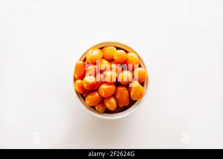 Bol en céramique rectangulaire et rond avec tomates cerises orange, jaune et rouge sur fond blanc et espace de copie Banque D'Images