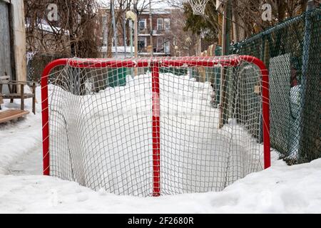 Un but de hockey et un petit anneau de glace fait maison pour les enfants dans une allée de Montréal, les voisins de la famille partagent l'espace de jeu, la culture locale Banque D'Images