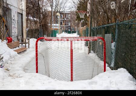 Un but de hockey et un petit anneau de glace fait maison pour les enfants dans une allée de Montréal, les voisins de la famille partagent l'espace de jeu, la culture locale Banque D'Images