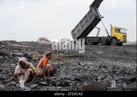 INDE, Jharkhand, Dhanbad Jharia, site d'extraction de charbon BCCL, charge lourde de camions Volvo, charriot, les gens collectent illégalement du charbon du champ de charbon à vendre sur le marché pour les moyens de subsistance / INDIEN, Dhanbad Jharia, BCCL Kohletagebau, Volvo Kipper laden Abraum ab, Menschen sammeln le Kohzum auf Verdem Markzum Banque D'Images