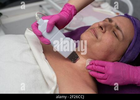 Dispositif de cavitation. L'esthéticienne guide doucement l'échographe sur le visage du client pour exfolier l'épiderme. Banque D'Images