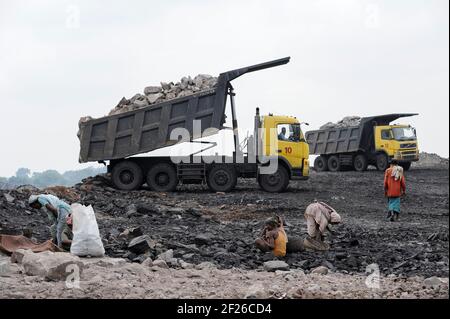 INDE, Jharkhand, Dhanbad Jharia, site d'extraction de charbon BCCL, charge lourde de camions Volvo, charriot, les gens collectent illégalement du charbon du champ de charbon à vendre sur le marché pour les moyens de subsistance / INDIEN, Dhanbad Jharia, BCCL Kohletagebau, Volvo Kipper laden Abraum ab, Menschen sammeln le Kohzum auf Verdem Markzum Banque D'Images