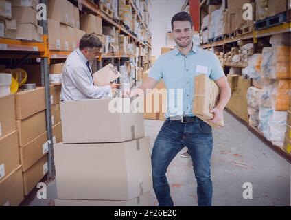 Composition d'un liveur souriant avec chariot de boîtes en carton en entrepôt Banque D'Images