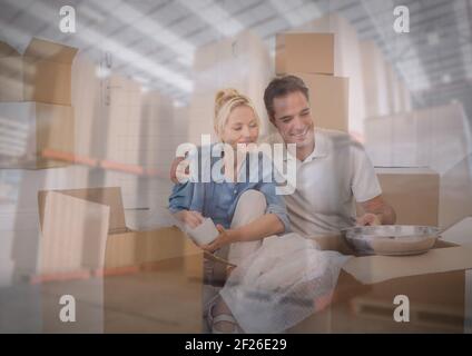 Composition de Happy couple déballant dans une nouvelle maison au-dessus des piles de boîtes en carton dans l'entrepôt Banque D'Images