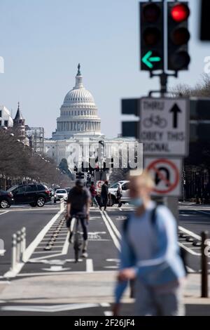 Washington, États-Unis. 10 mars 2021. Les gens sont vus à un carrefour abandonné par le bâtiment du Capitole des États-Unis à Washington, DC, les États-Unis, le 10 mars 2021. La Chambre des représentants des États-Unis a approuvé mercredi la version finale du projet de loi d'allègement COVID-19 de 1.9 billions de dollars américains, l'envoyant au bureau du président Joe Biden pour sa signature. Credit: Liu Jie/Xinhua/Alay Live News Banque D'Images