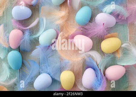 Concept joyeuses pâques. Œufs et plumes de Pâques colorés sur fond de bois. Pose à plat. Banque D'Images