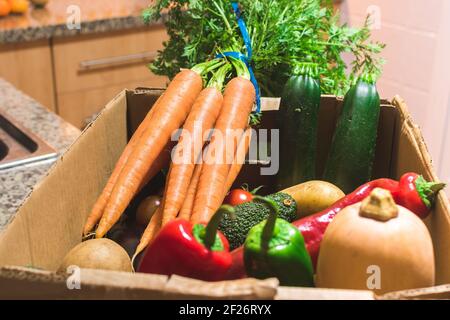 Détail d'une boîte pleine de fruits et légumes biologiques sur un comptoir de cuisine Banque D'Images