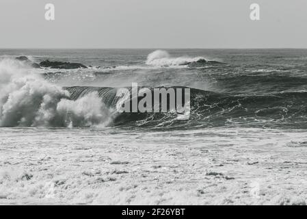 Une photo en niveaux de gris de grandes vagues qui se brisent sur la mer - parfait pour l'arrière-plan Banque D'Images