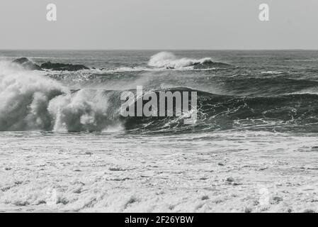 Une photo en niveaux de gris de grandes vagues qui se brisent sur la mer - parfait pour l'arrière-plan Banque D'Images